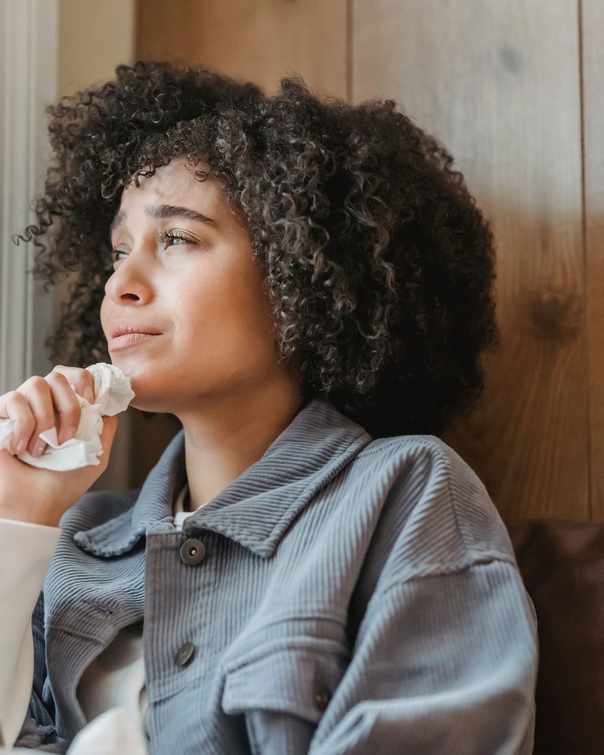 Une femme pensive près d’une fenêtre