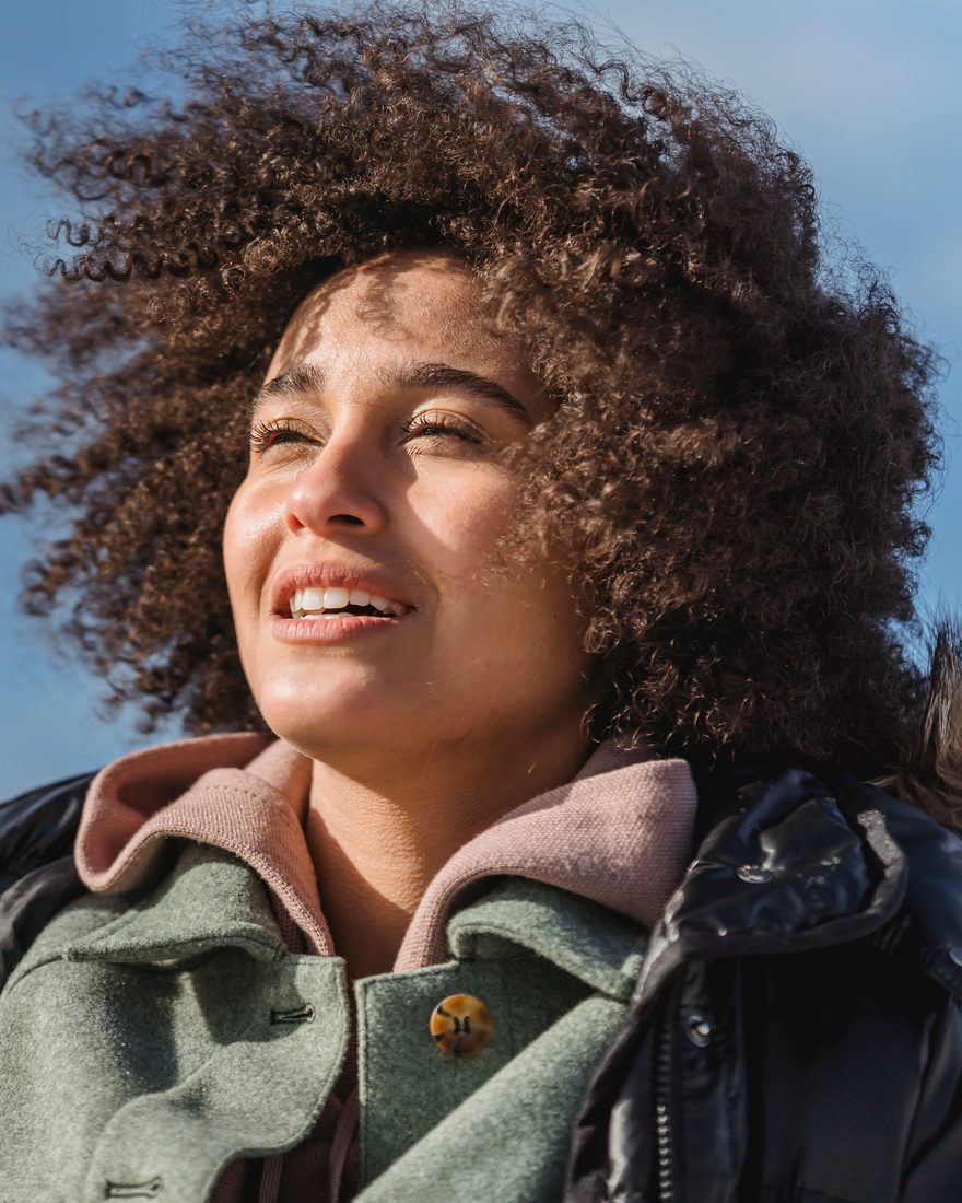 Une femme souriante, apaisée, le visage au soleil